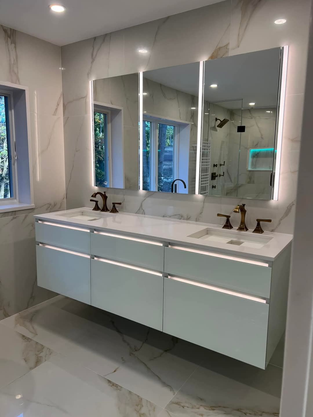Une salle de bain avec deux lavabos et trois miroirs.