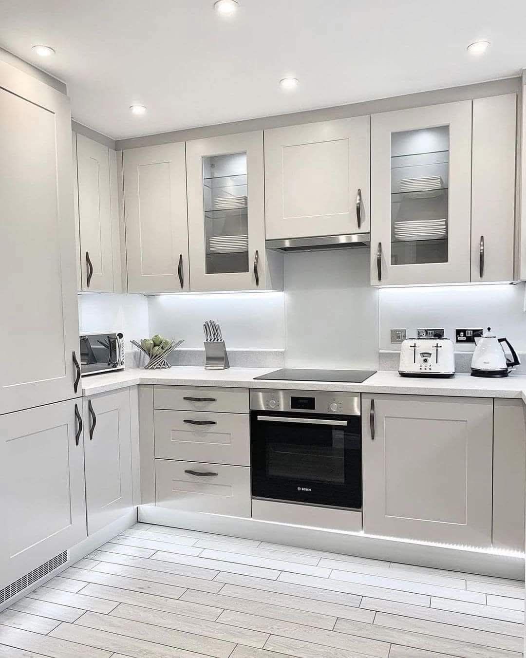 Une cuisine avec des armoires blanches, une cuisinière, un four grille-pain et un micro-ondes.
