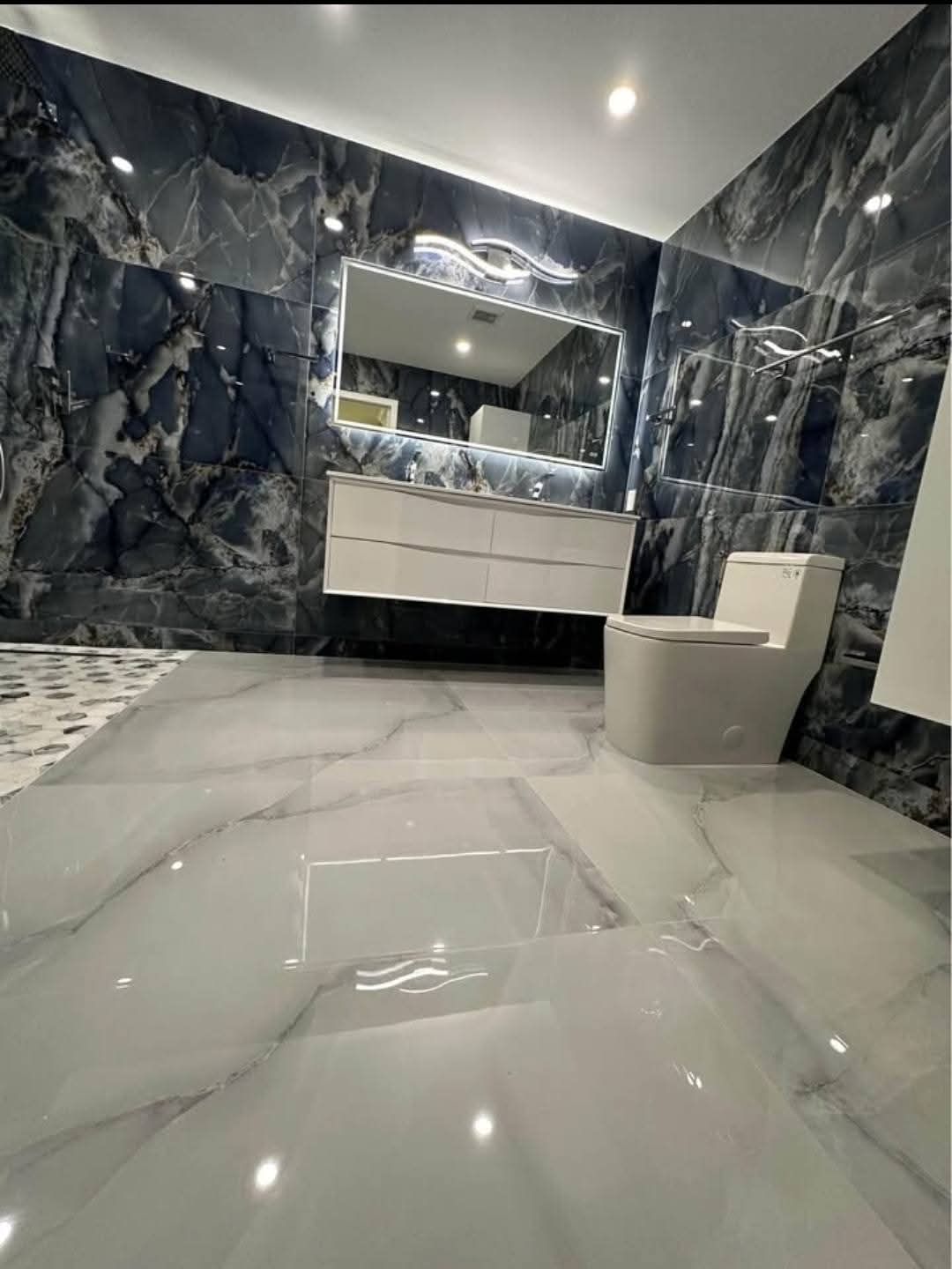 Une salle de bain avec WC, lavabo et miroir.