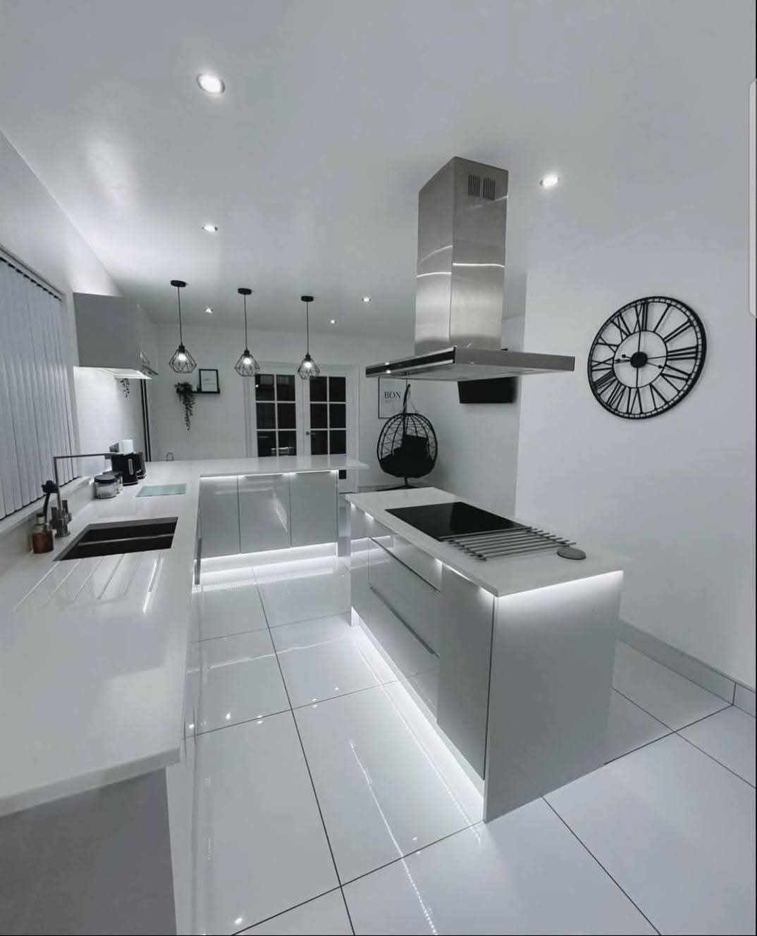 Une cuisine avec des armoires blanches et une horloge sur le mur