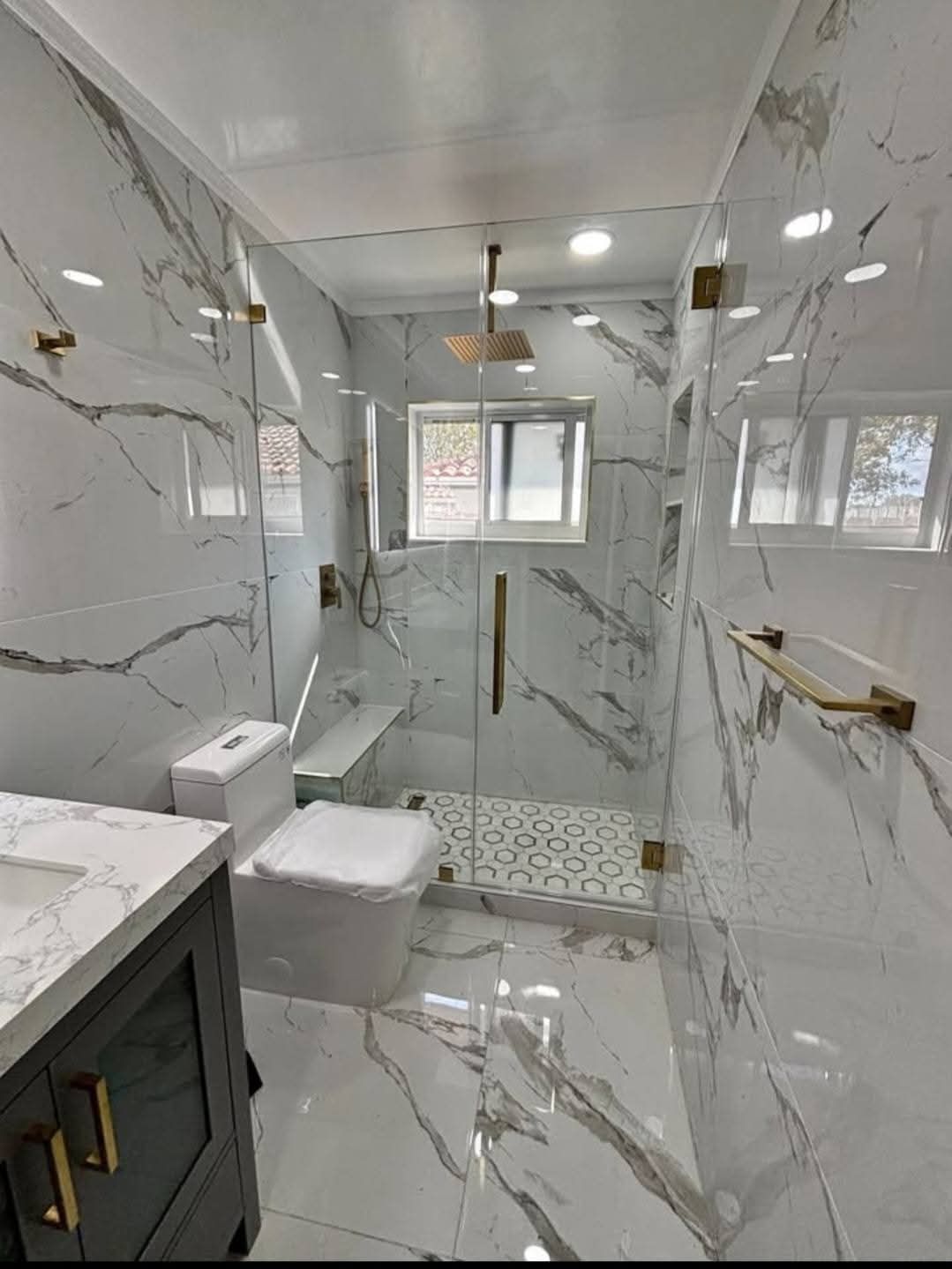 Une salle de bain avec WC, lavabo, douche et carrelage en marbre.