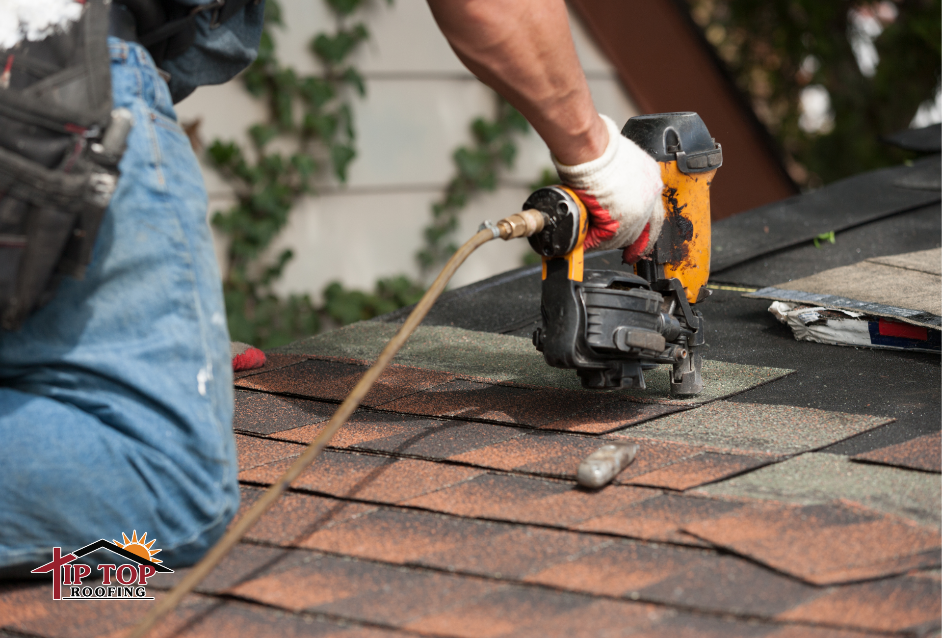 Roofing contractor installing asphalt shingles on a sloped residential roof.