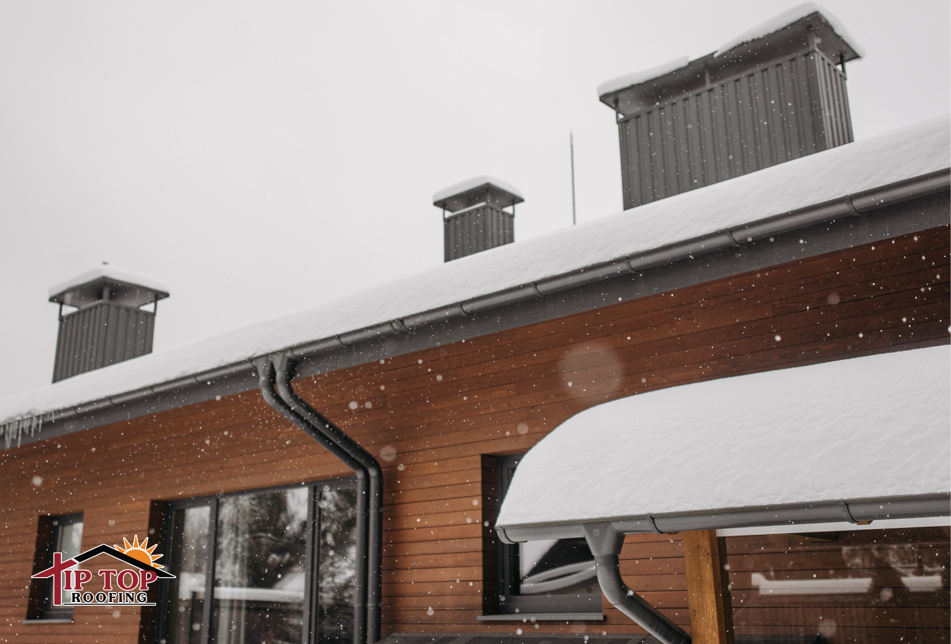 A home and its roof are covered in snow while it is snowing. 