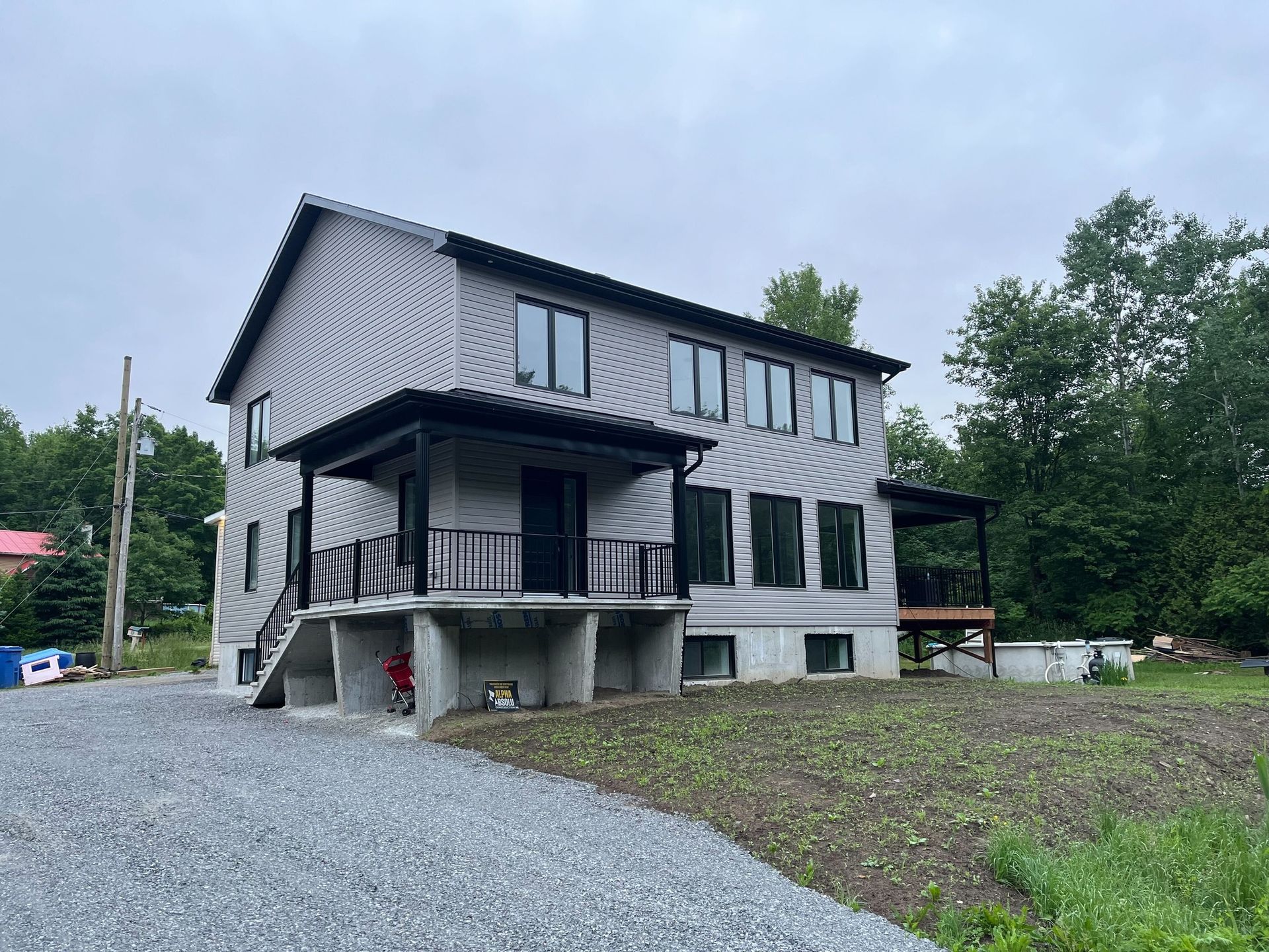 Une grande maison est située sur un terrain en gravier au milieu d'un champ.