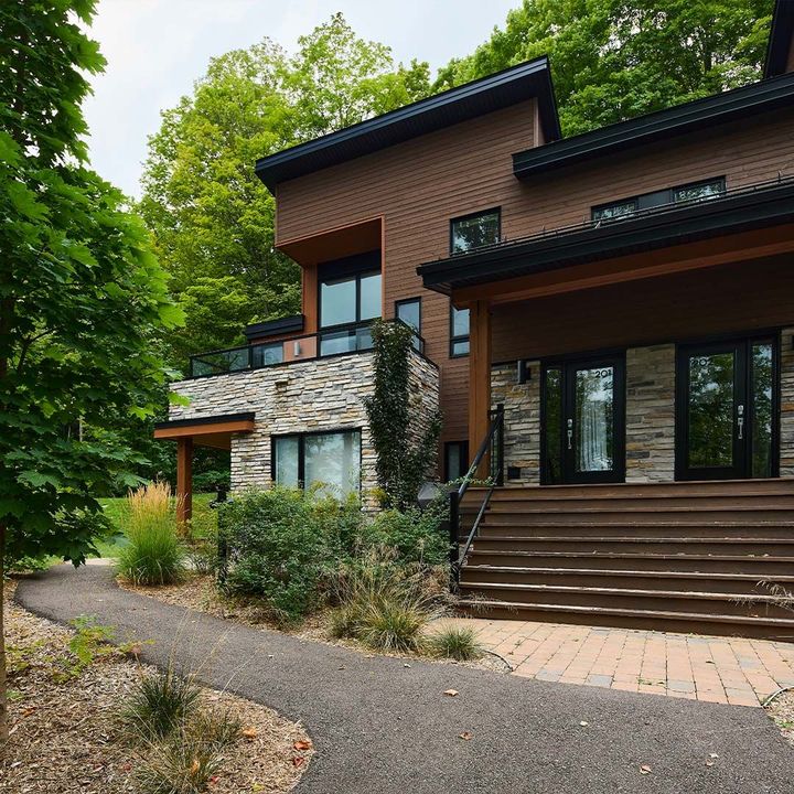 Une grande maison avec beaucoup de fenêtres est entourée d'arbres.
