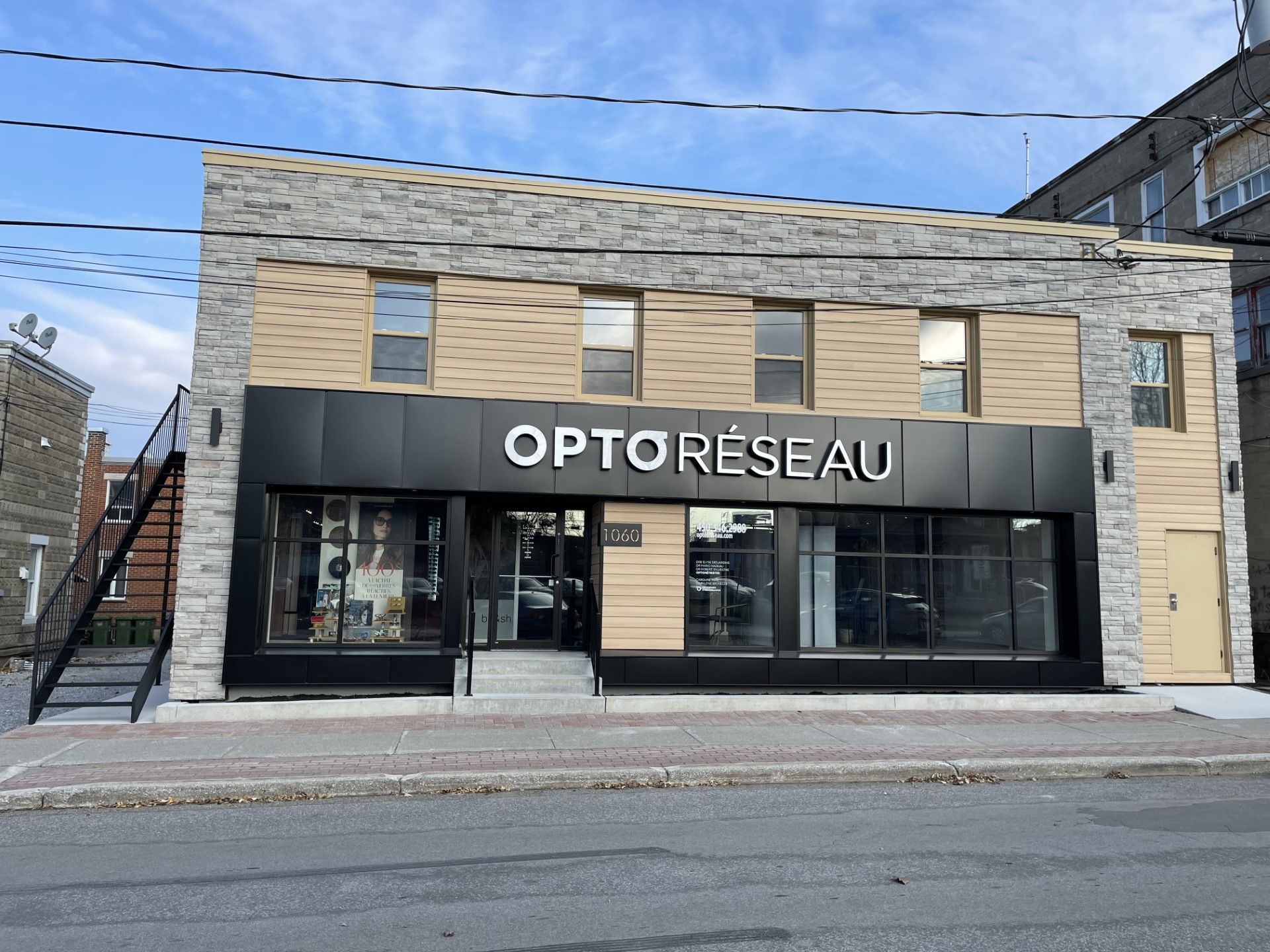 Un grand bâtiment en briques avec un panneau noir sur lequel est écrit optoresseau.