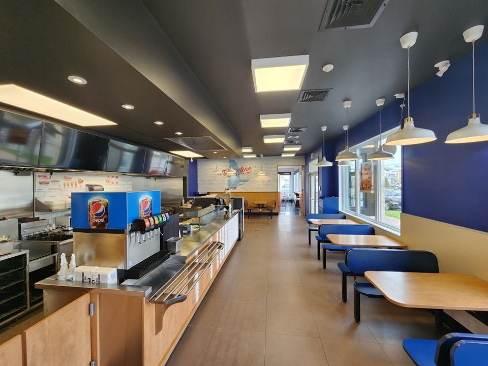 L'intérieur d'un restaurant de restauration rapide avec des tables et des chaises et une machine à Pepsi.
