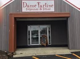 La devanture d'un restaurant avec un panneau indiquant dame tartine déjeuner & dîner.