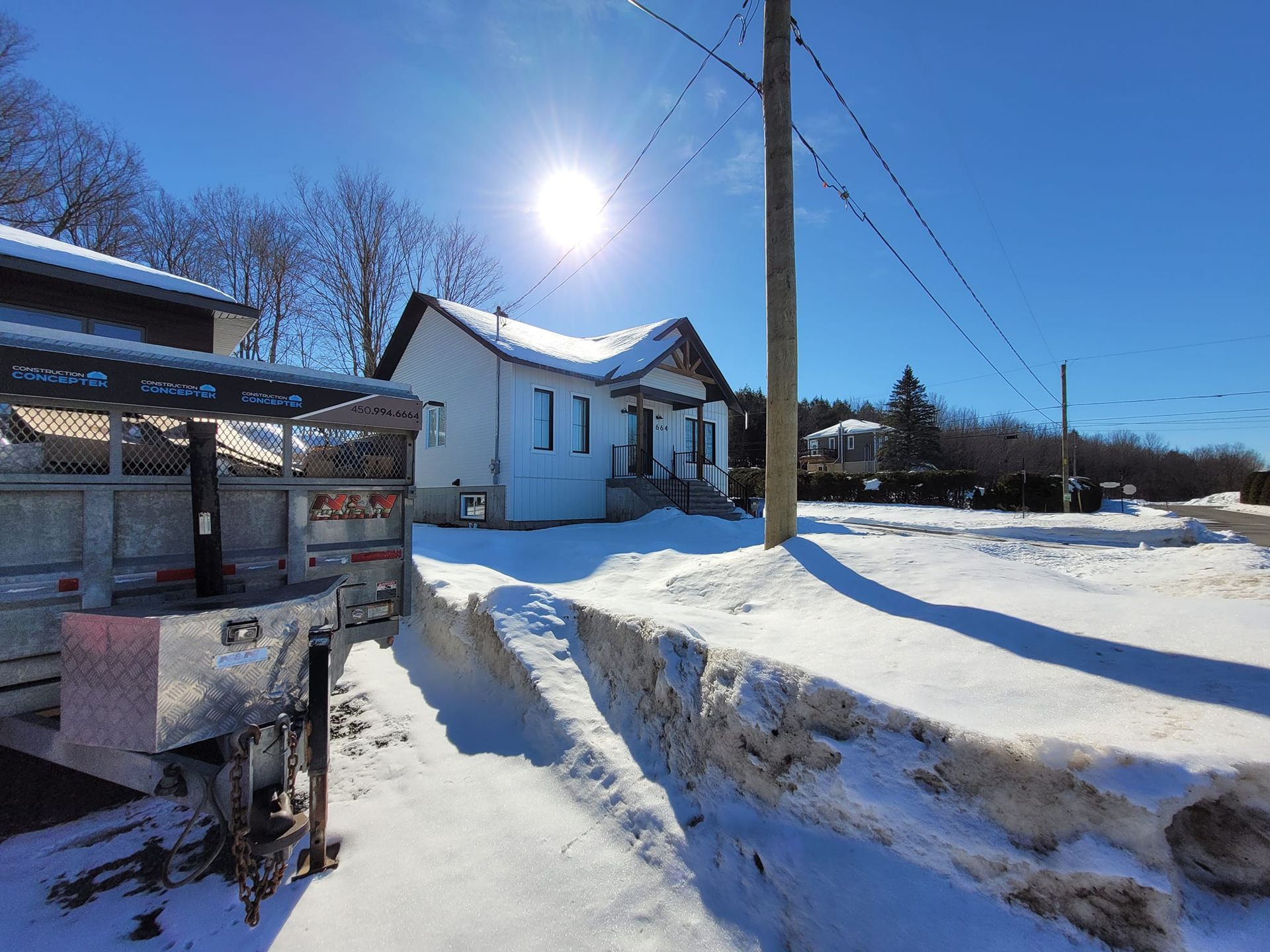 Une remorque est garée devant une maison couverte de neige.
