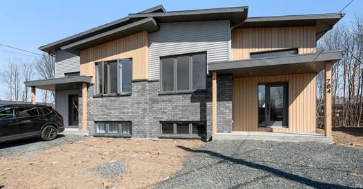 Une grande maison avec une voiture garée devant.
