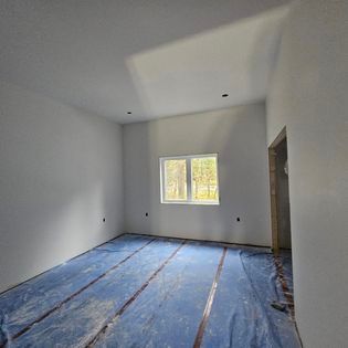 Une pièce vide avec une bâche bleue sur le sol et une fenêtre.