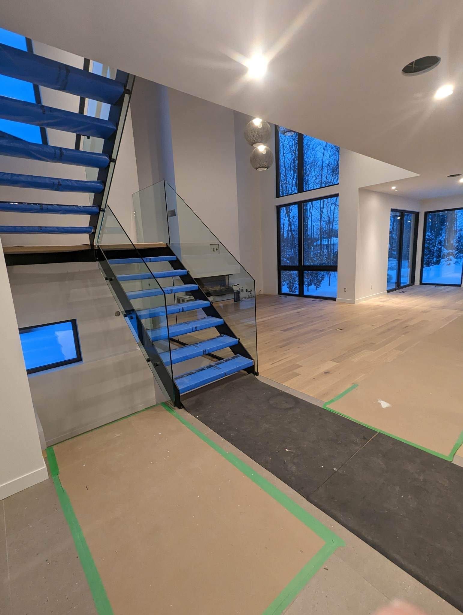 Un escalier avec des marches bleues et une rampe en verre dans une pièce vide.