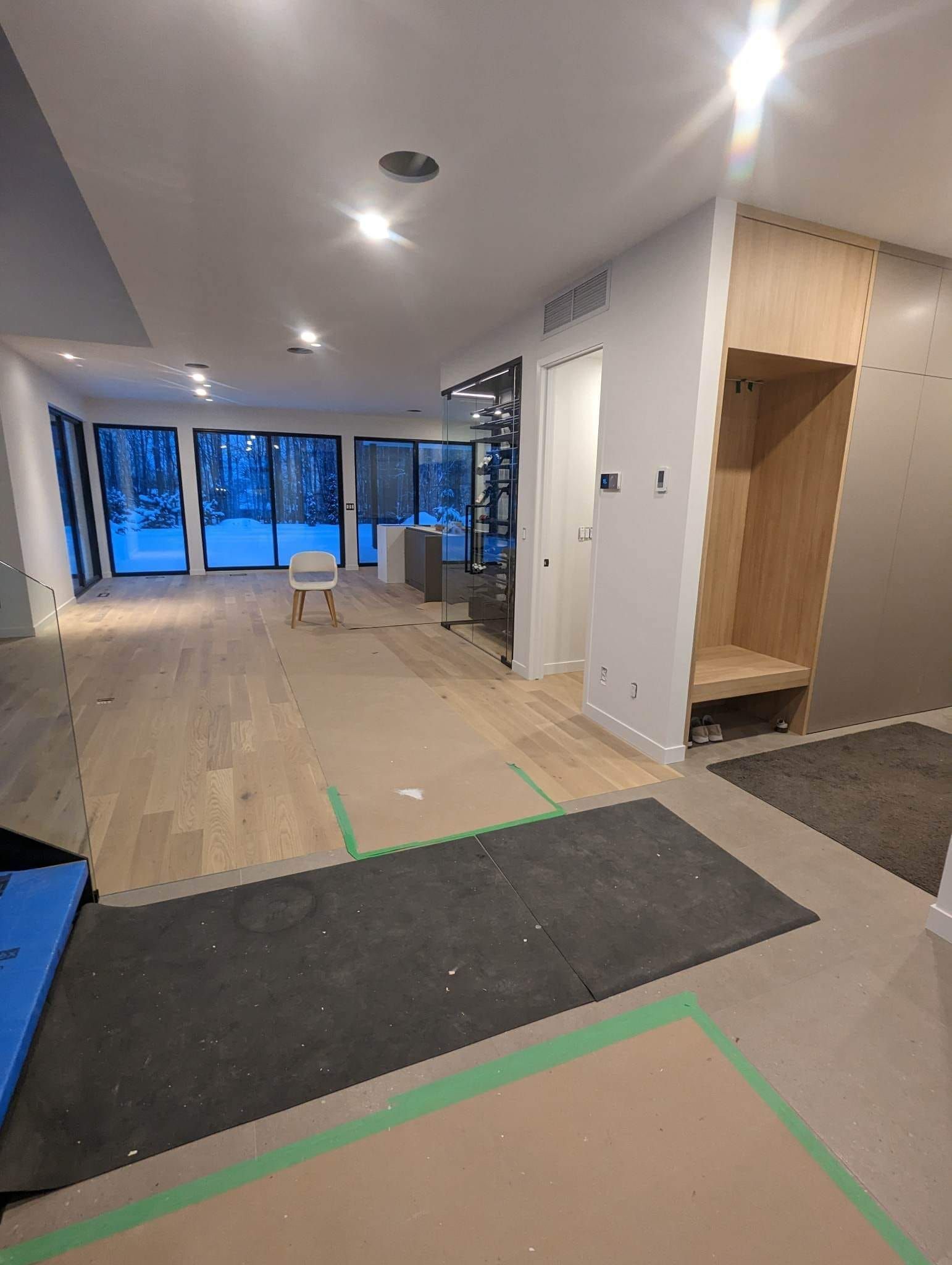 Une grande pièce avec parquet et beaucoup de fenêtres est en cours de rénovation.