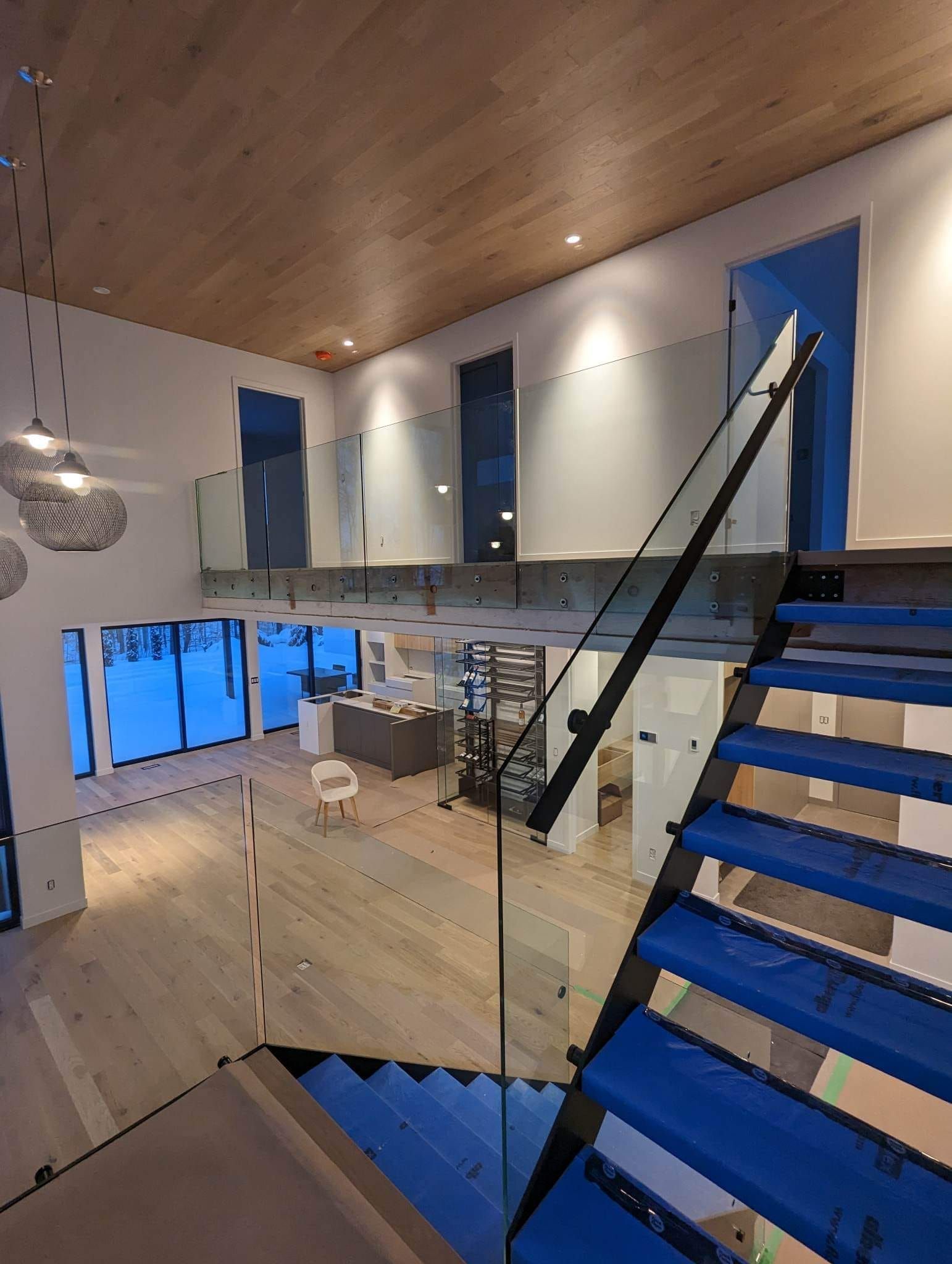 Un escalier avec des marches bleues et une rampe en verre dans une maison.
