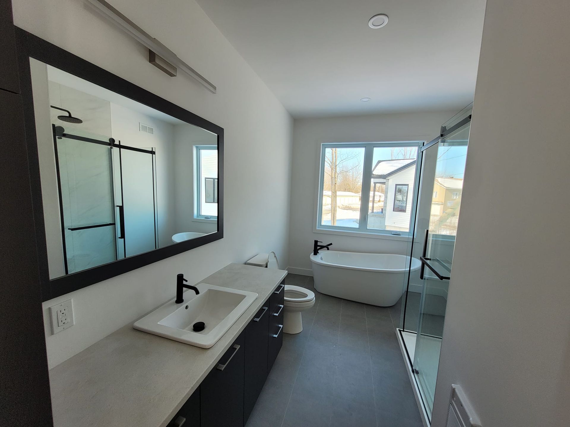 Une salle de bain avec lavabo, WC, baignoire et miroir.
