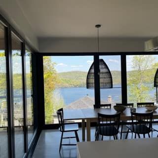 Une salle à manger avec une table et des chaises et une vue sur un lac.