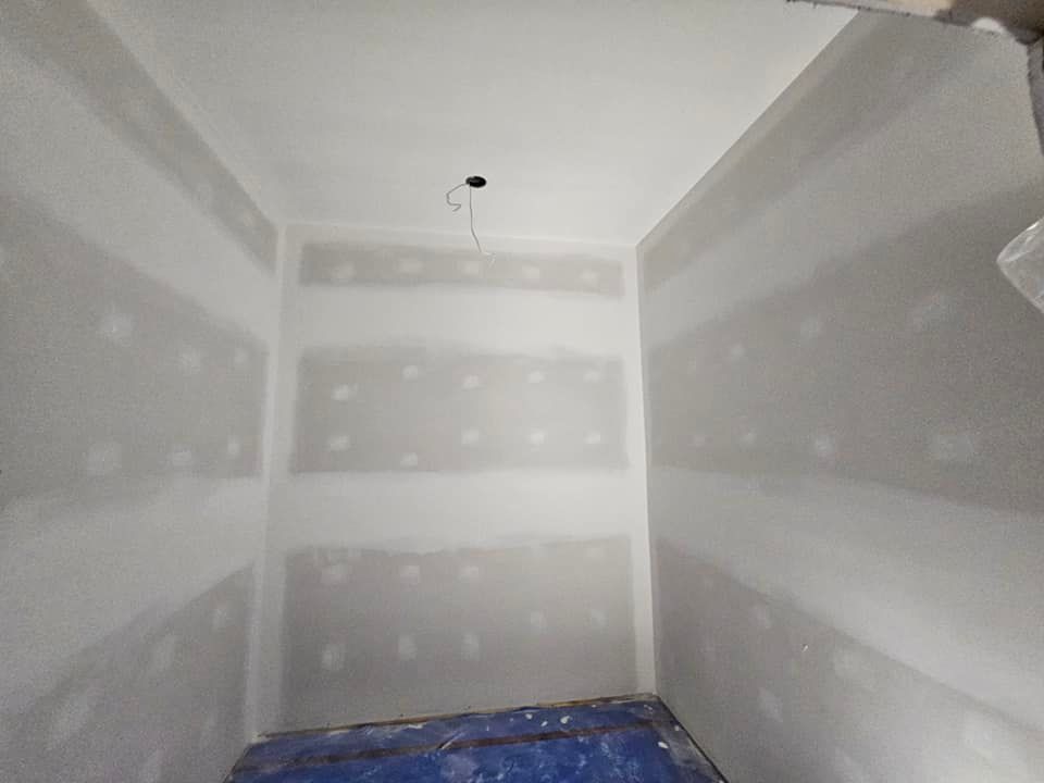 Une pièce avec des murs blancs et une bâche bleue sur le sol.