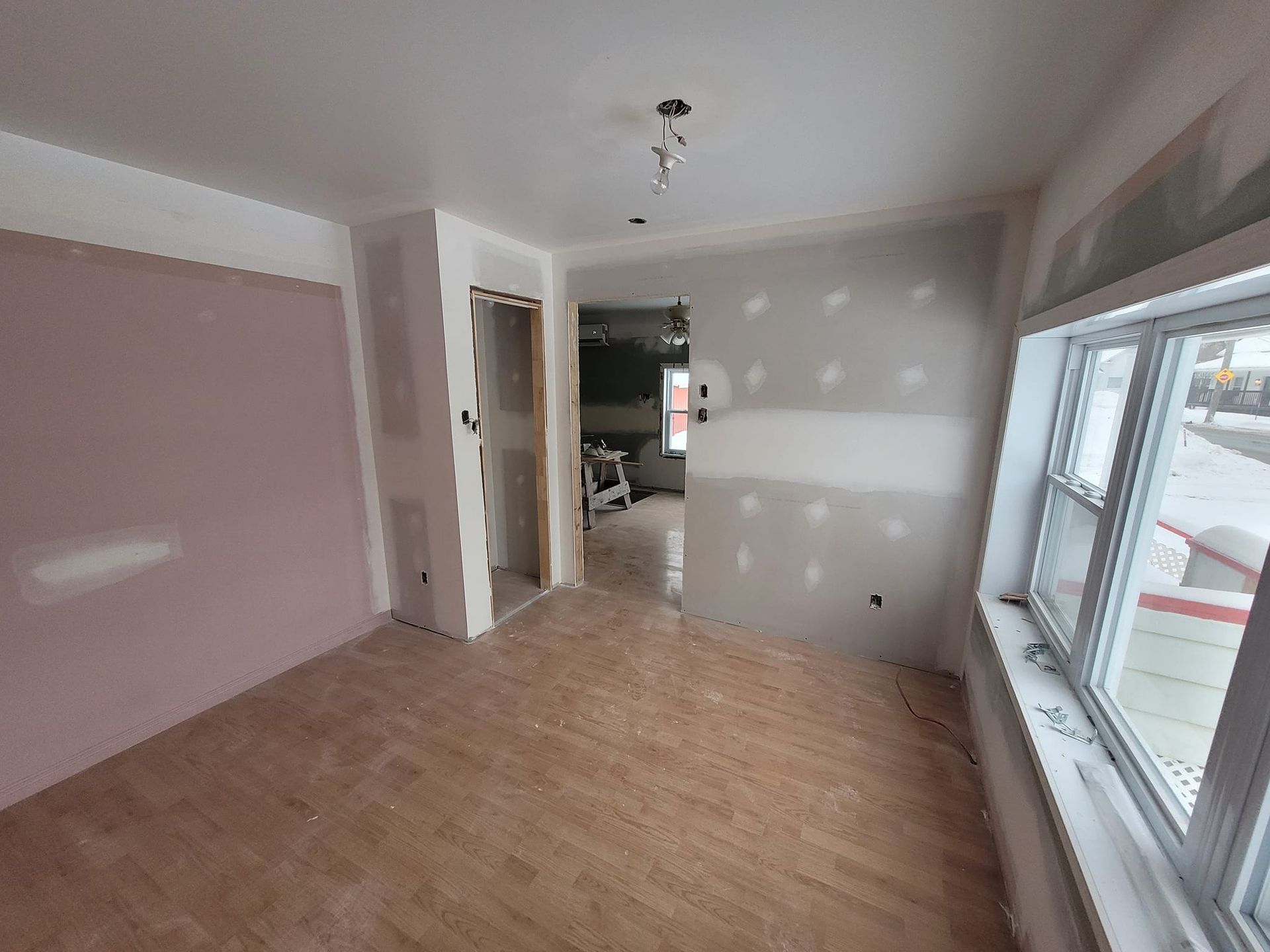 Une pièce avec un plancher en bois et deux fenêtres en cours de construction.