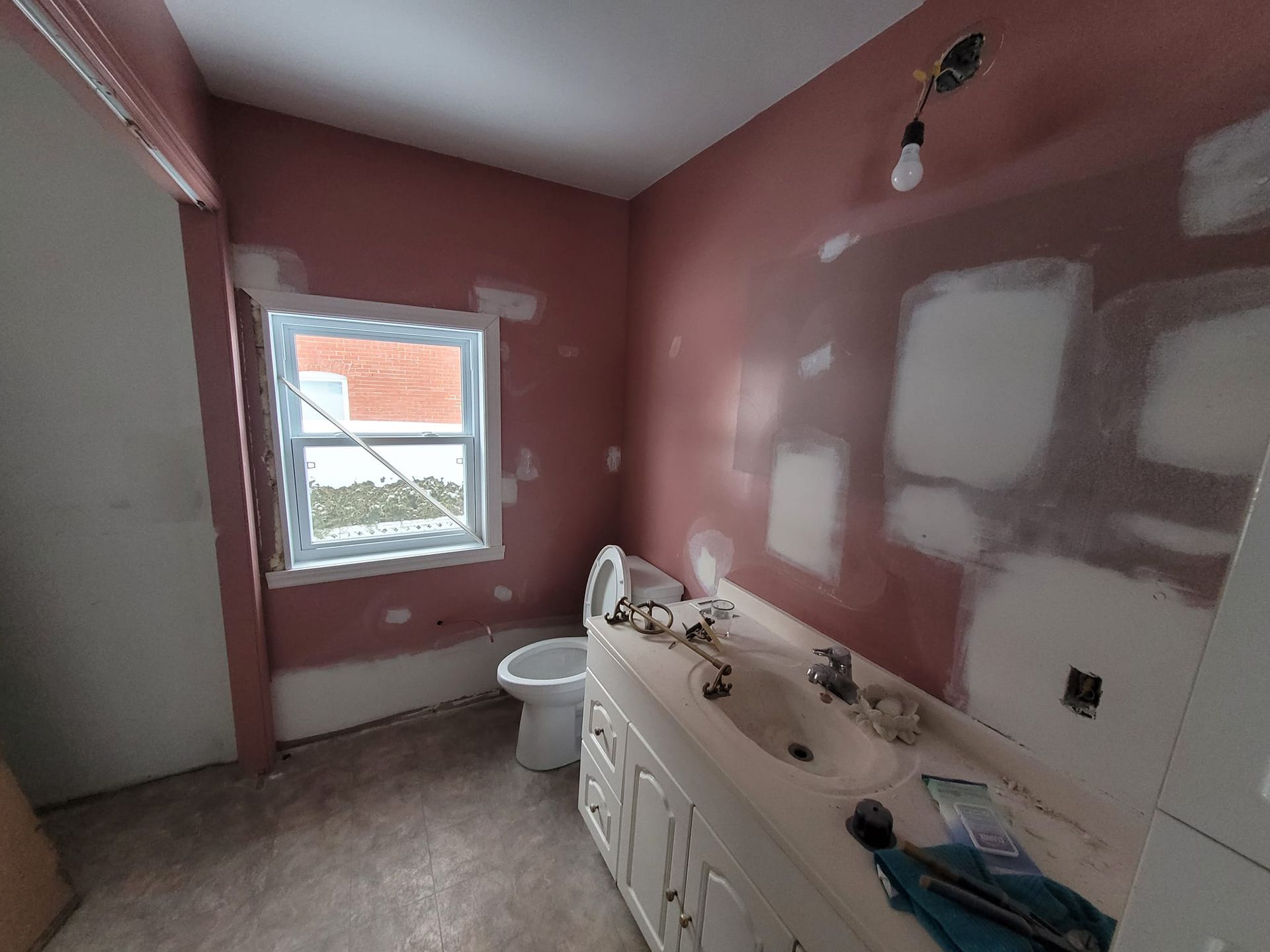 Une salle de bain avec lavabo, toilettes et fenêtre.