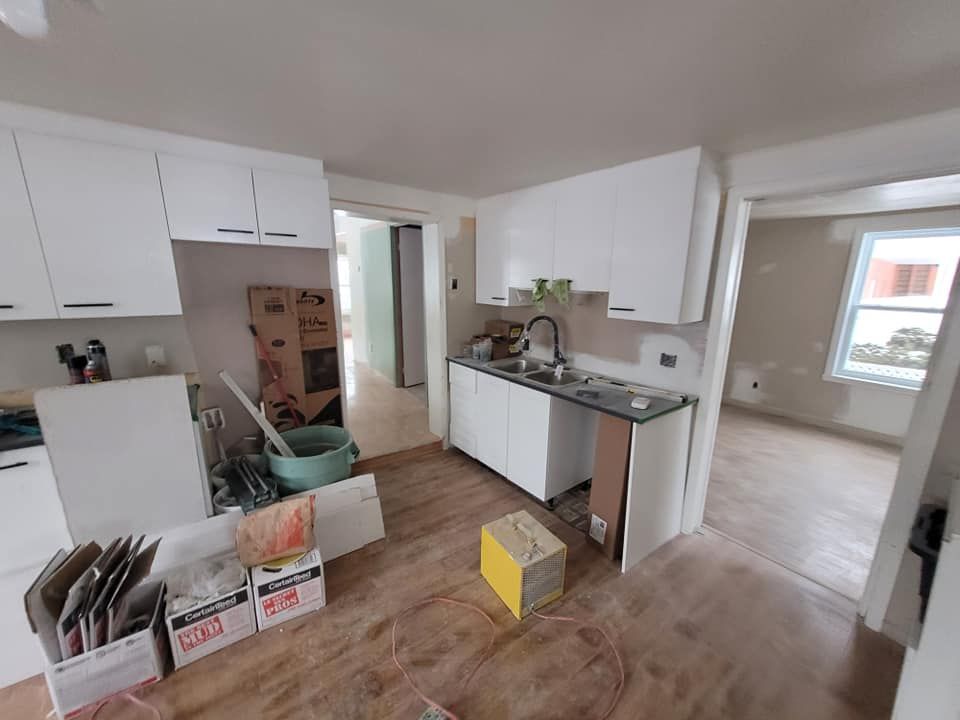 Une cuisine avec des armoires blanches et un évier dans une maison en construction.