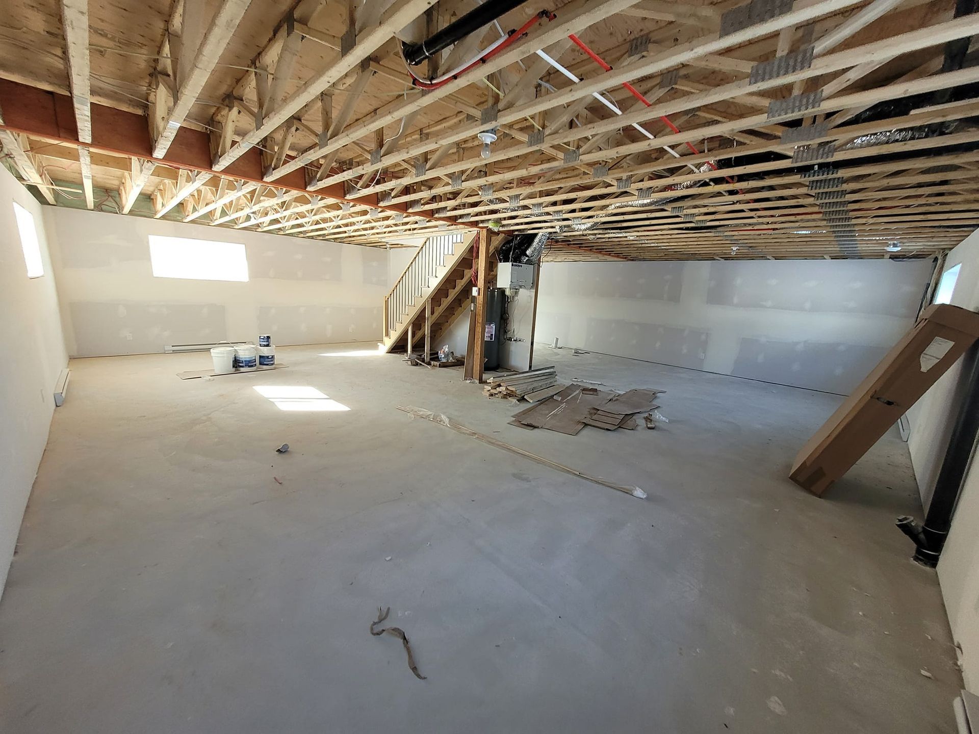 Un sous-sol en construction avec un escalier montant au deuxième étage.