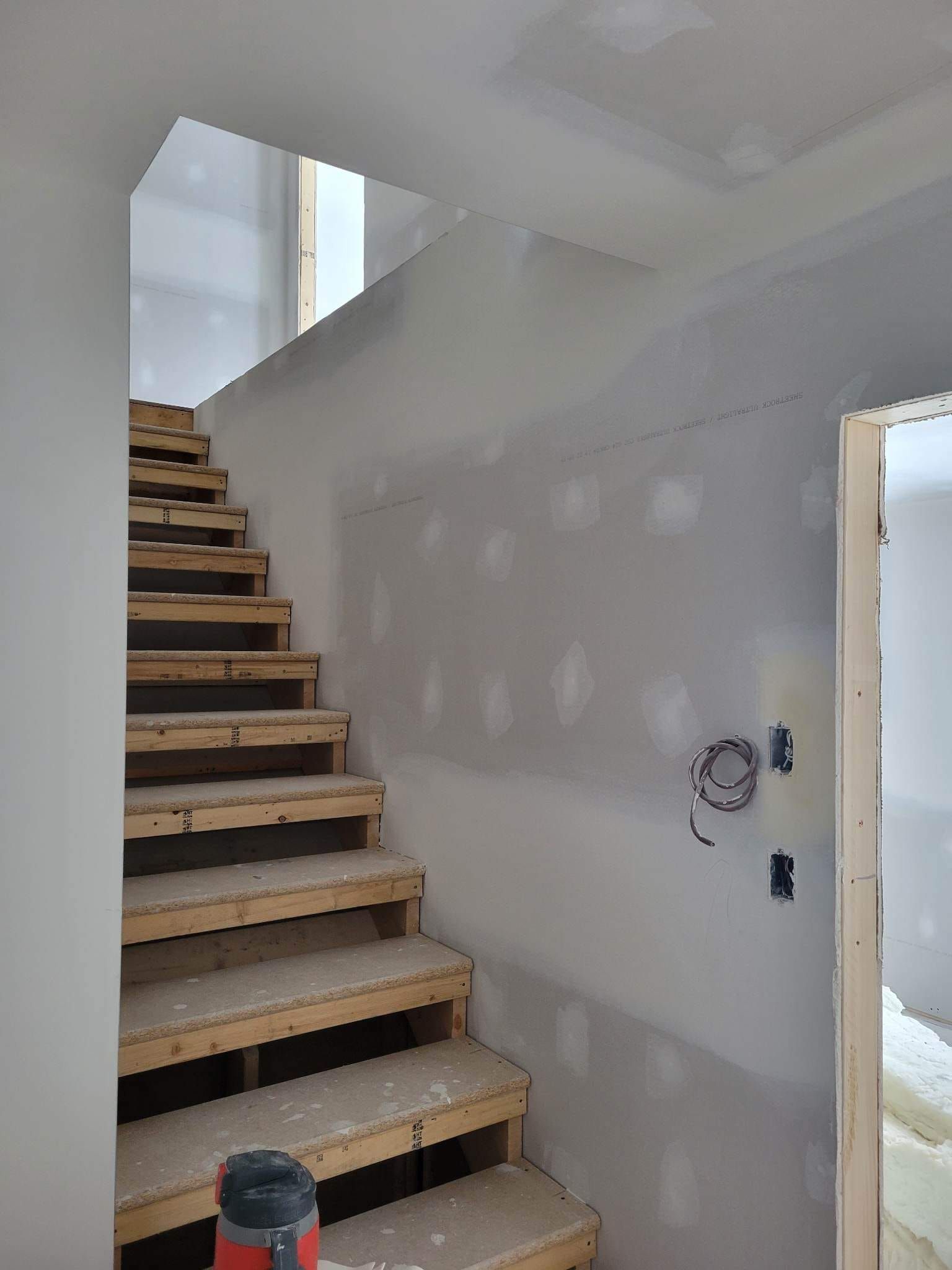 Un escalier est en cours de construction dans une pièce avec un mur blanc.