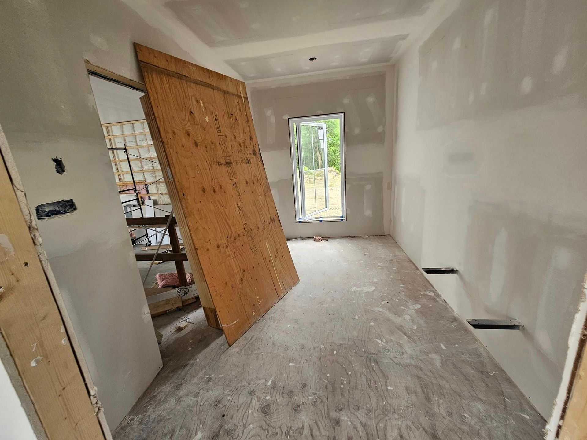 Une pièce en construction avec une porte en bois et une fenêtre.