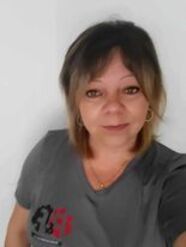 Une femme en chemise grise prend un selfie.