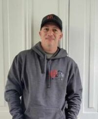 Un homme portant un chapeau et un sweat à capuche se tient devant une armoire blanche.