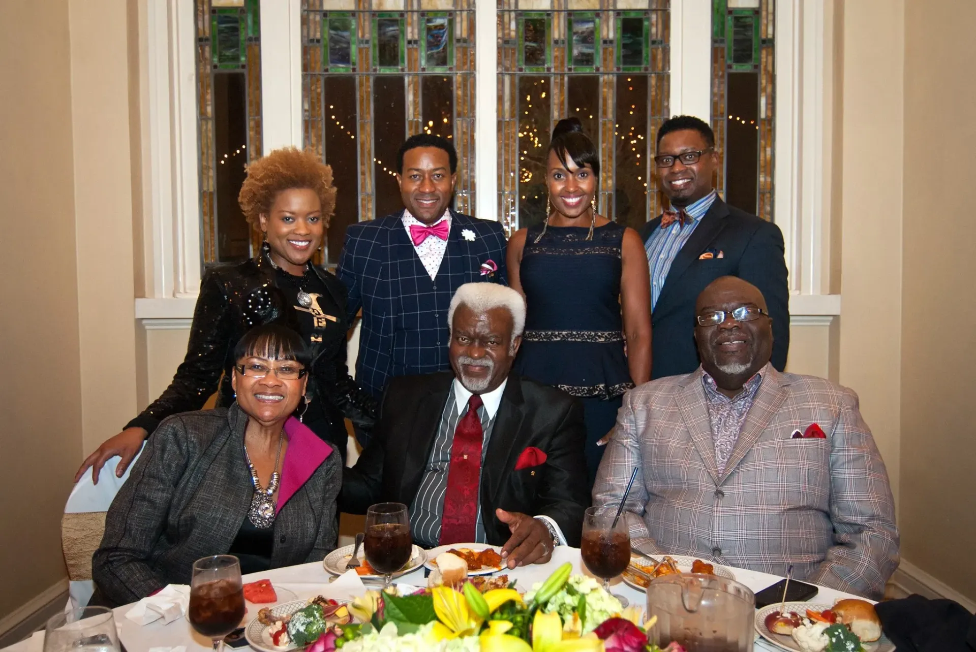 A group of people are posing for a picture at a table with food.
