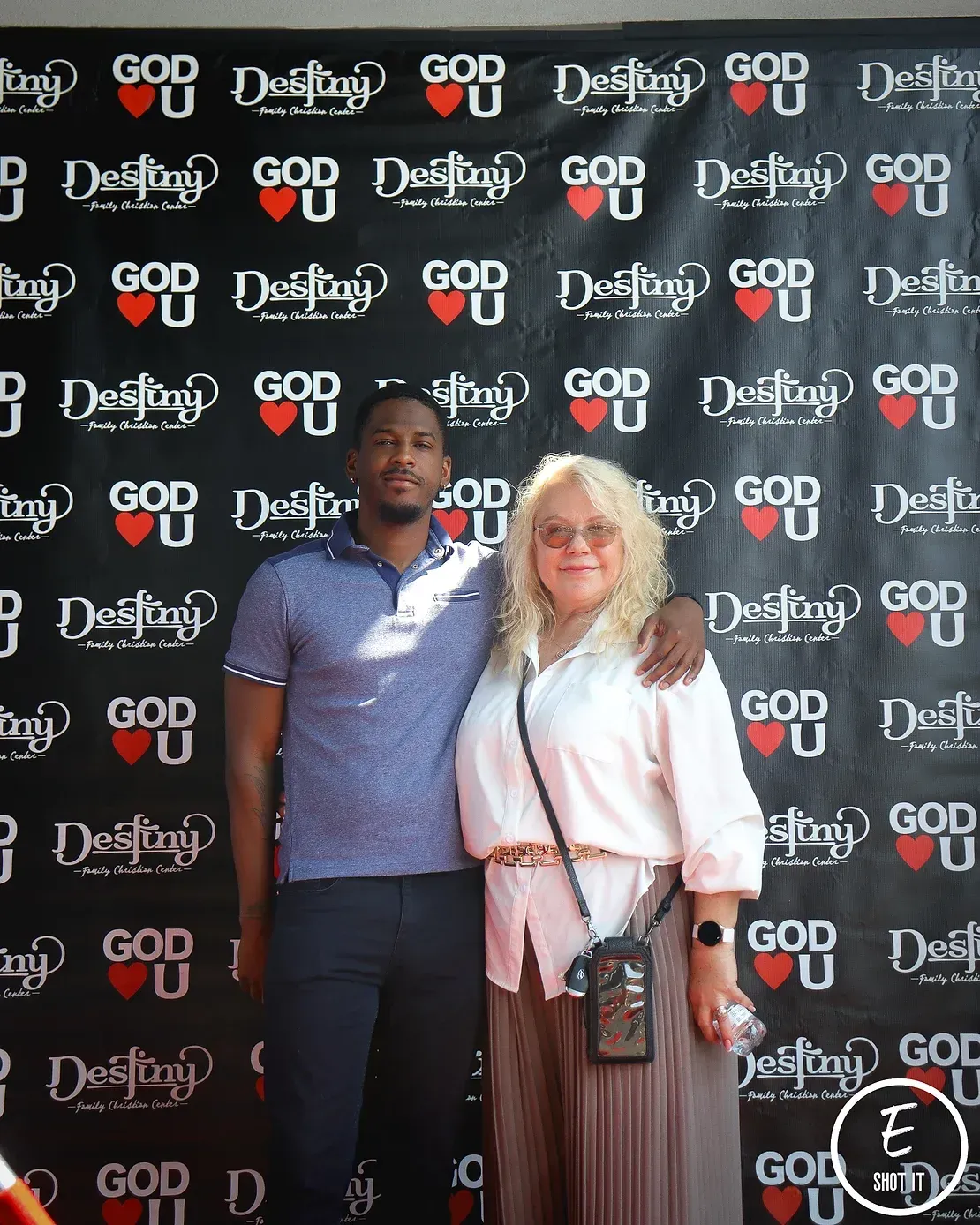 A man and a woman are posing for a picture in front of a wall that says god