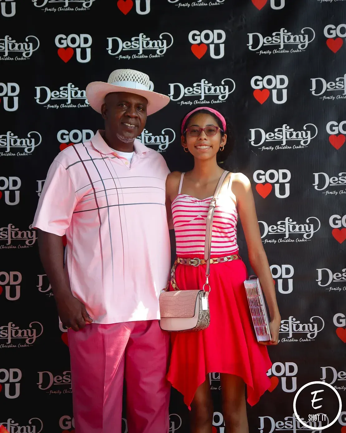 A man and a girl pose in front of a wall that says god destiny