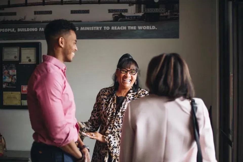 A group of people are standing in a room talking to each other.