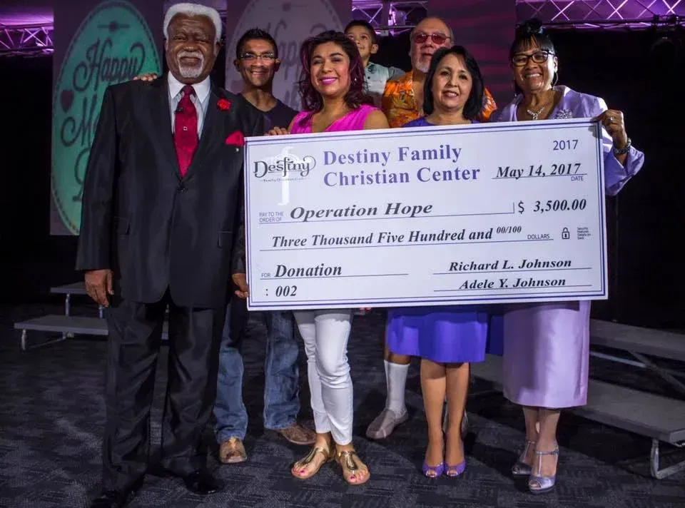 A group of people holding a large check for destiny family christian center