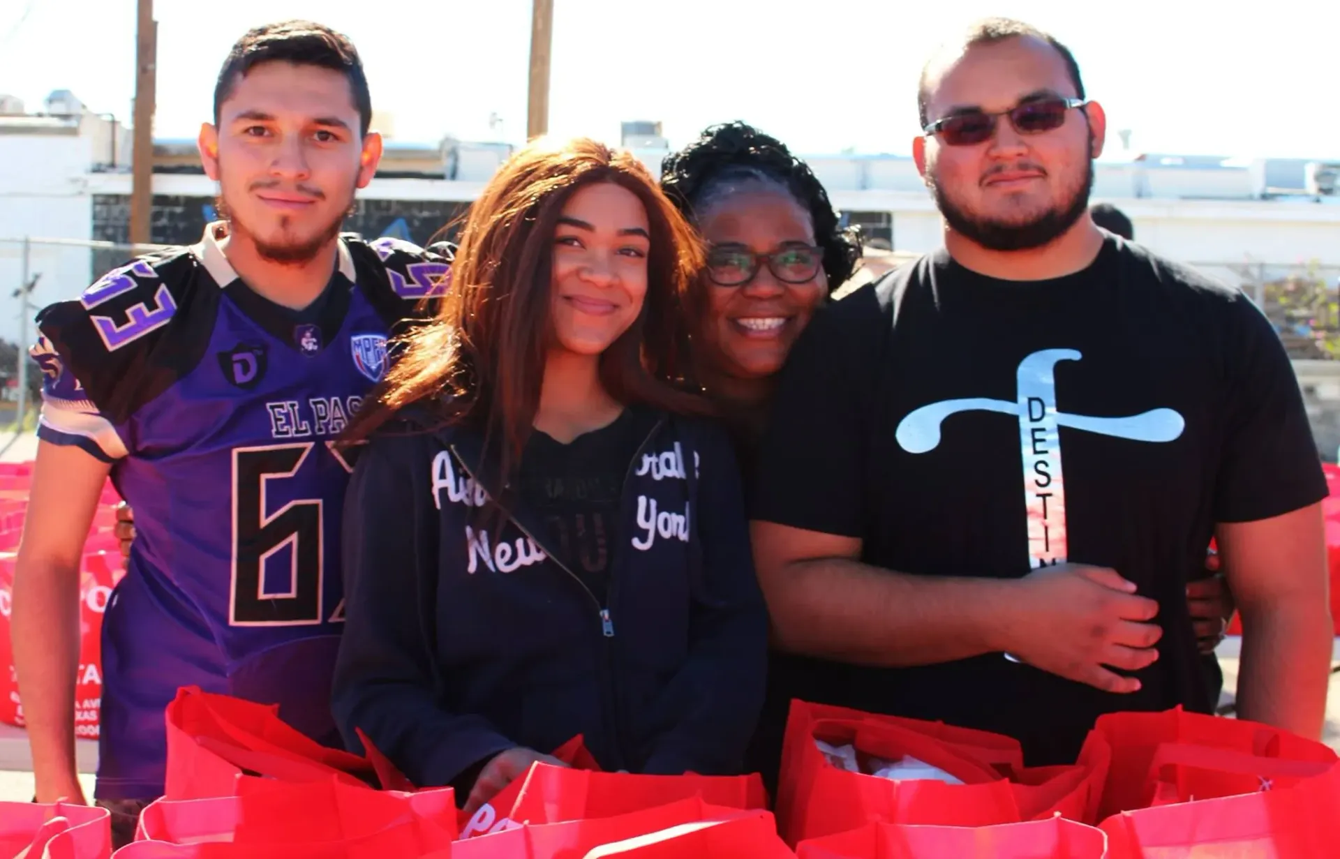 A group of people are posing for a picture while holding red bags.