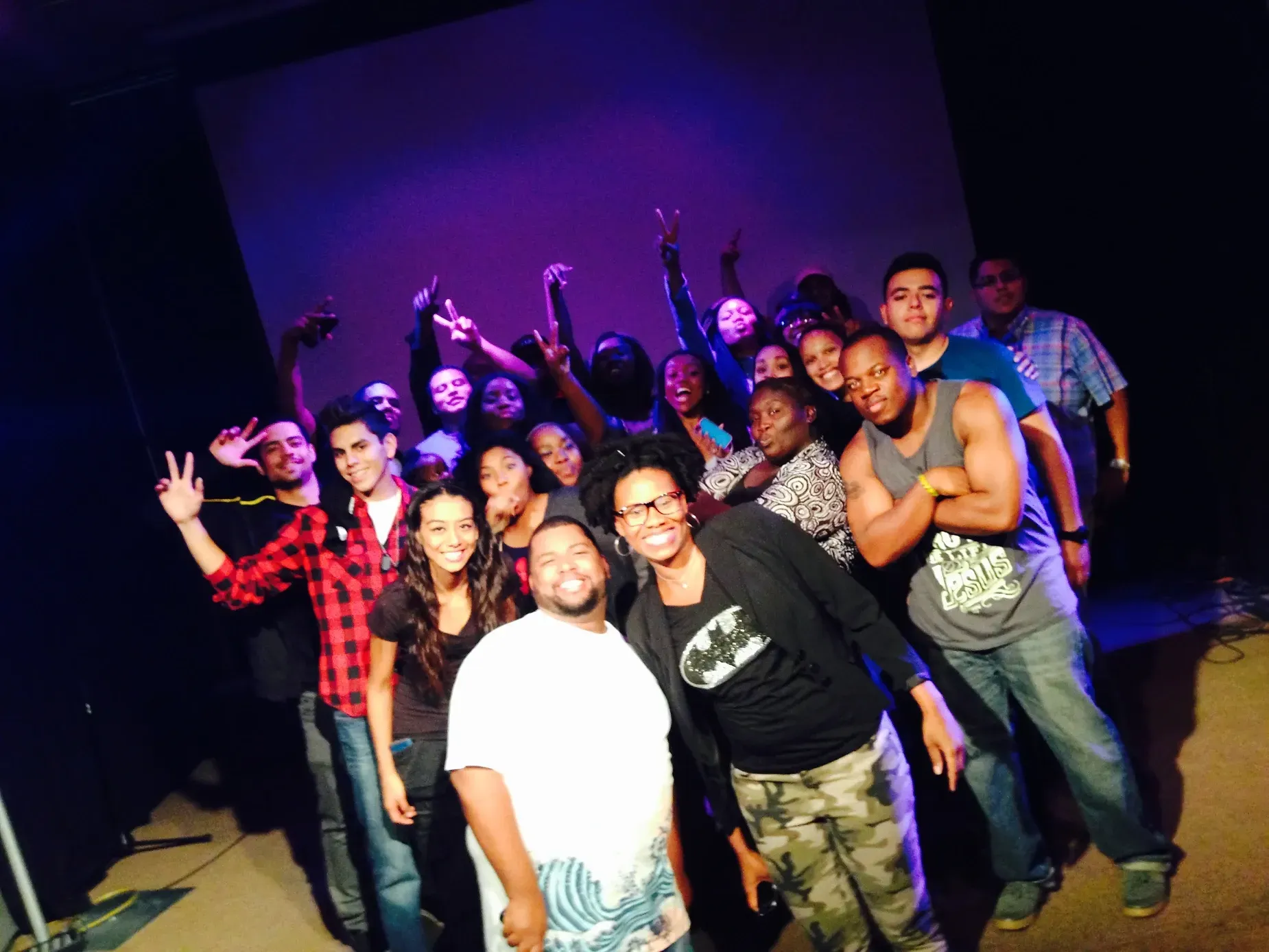 A group of people posing for a picture with purple lights behind them