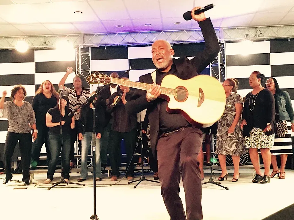 A man is singing into a microphone while holding a guitar.