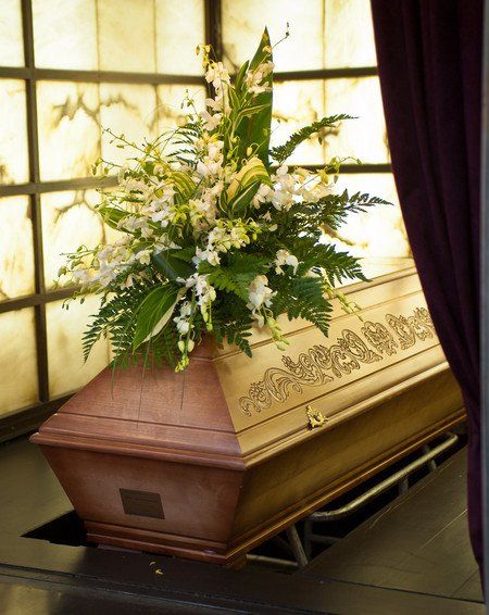 Wooden coffin with funeral flowers in crematorium