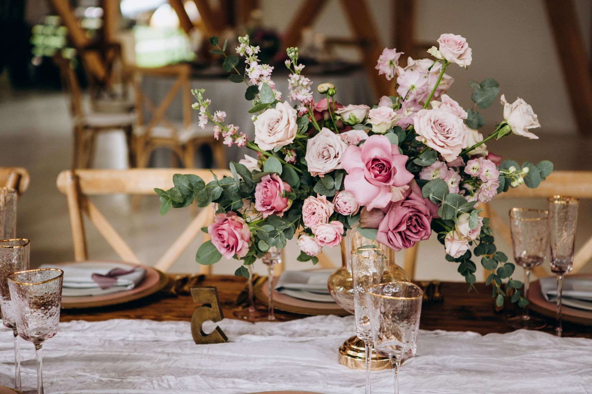 Roses in a vase on a table set for rustic wedding reception