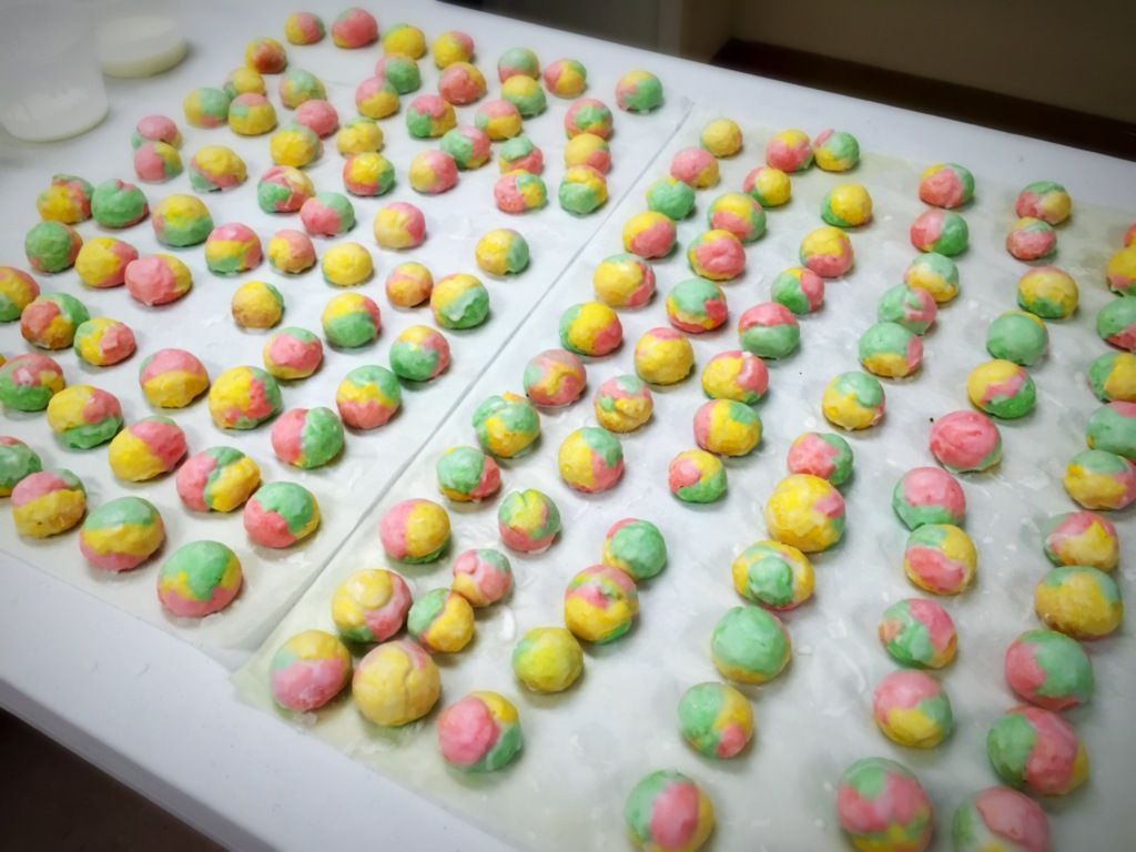 Hundreds of colorful dough balls in pink, yellow, and green.