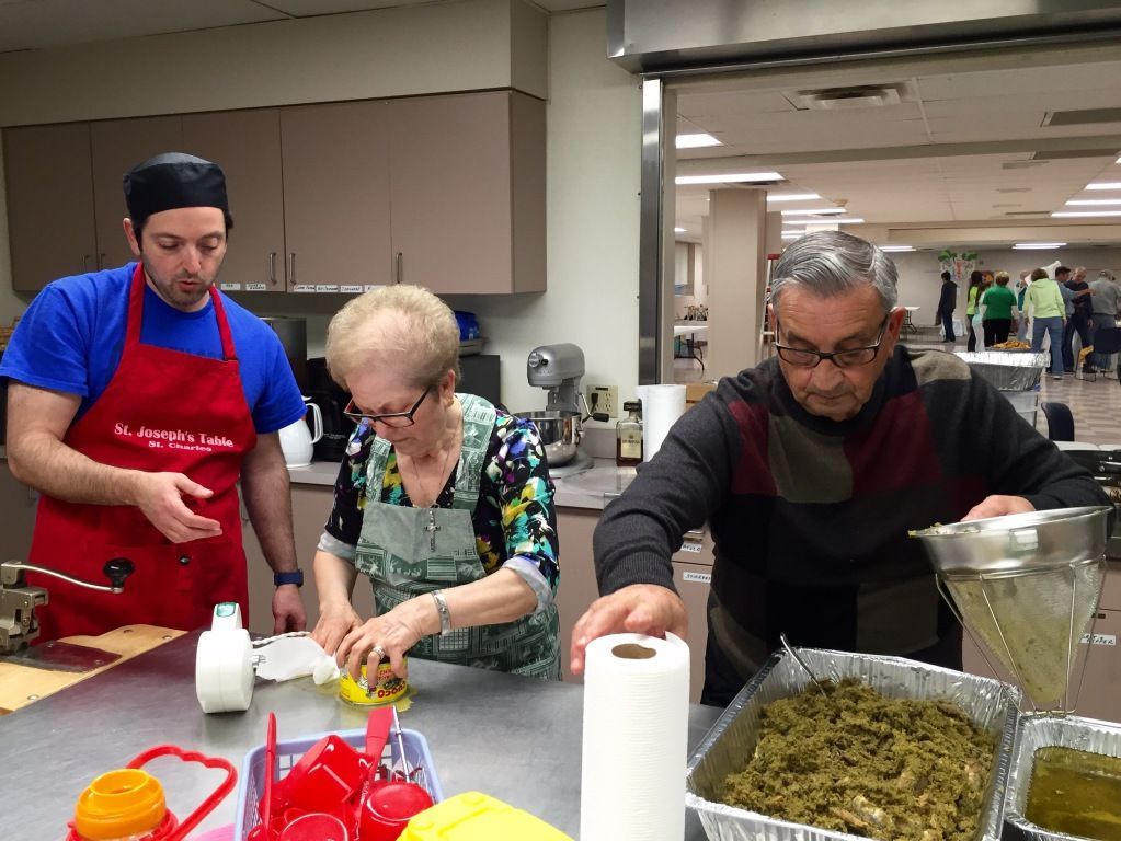 Three people in a kitchen are preparing food.