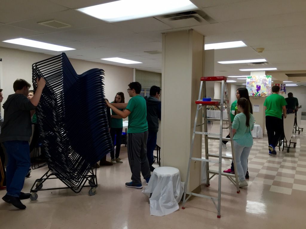 Group of young people in a room setting up for an event.