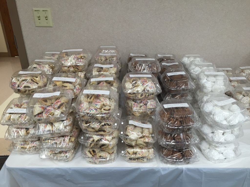Stacks of assorted baked goods in clear plastic containers, arranged on a table.
