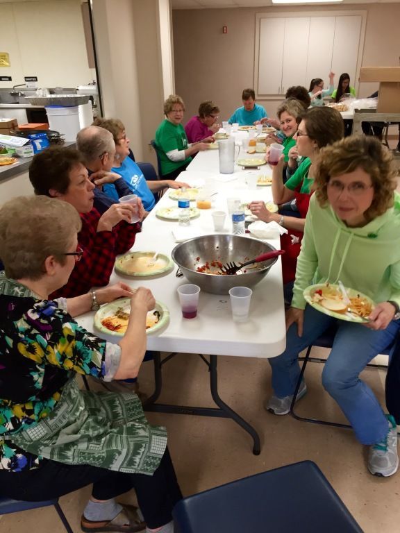 A group of people enjoys a meal together at a long table indoors. 