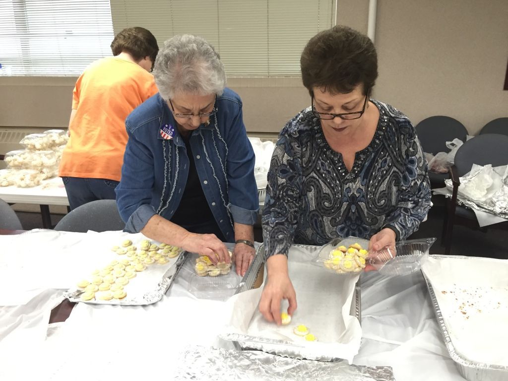 Two women work together sorting cookies into trays.