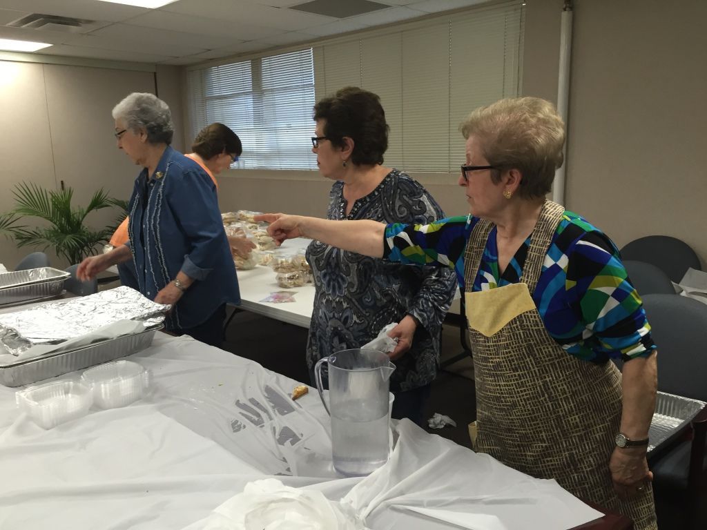 Three women are busy preparing food at a table.