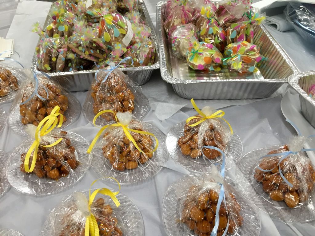 Festive treats wrapped in clear plastic with yellow and blue ribbons are displayed on a table. 