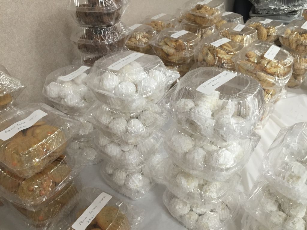 Stacks of assorted baked goods, like cookies and pastries, wrapped in clear plastic on a table.