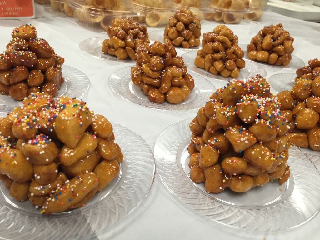 Piles of golden, glazed pastries topped with colorful sprinkles.
