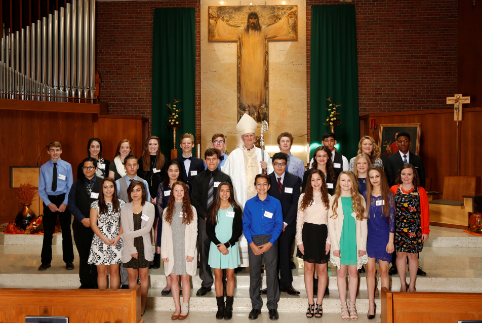 A group of young adults stands on church steps, dressed formally.